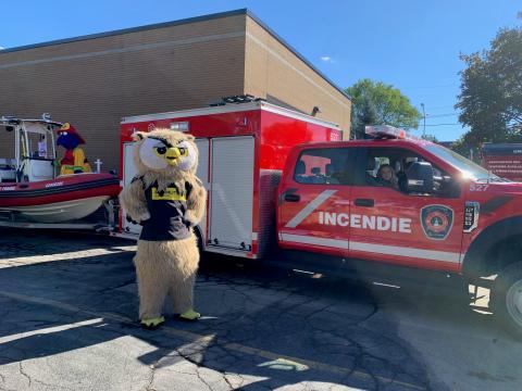 Une mascotte d'hibou à côté d'un camion de pompier