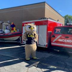 Une mascotte d'hibou à côté d'un camion de pompier