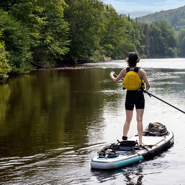 Personne qui fait de la planche a pagaie sur une riviere du quebec